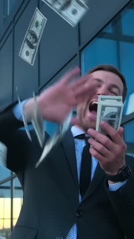 A man in a suit and tie is casually tossing money into the air