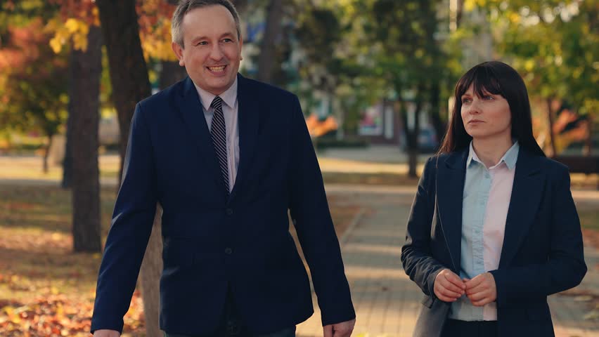 Business people man woman communicate, discuss business, team work. Business woman partners successful cooperation, nature. Businessmen in suits talking, walking through, city autumn park. Politicians Royalty-Free Stock Footage #3483739483