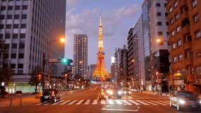 street view of business area with view of Tokyo Tower in sunset to night time with some traffic on road,Tokyo Tower landmark famous tourist attraction in 4K UHD video in japan