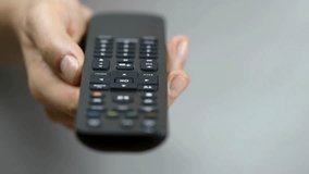 Closeup shot of man flipping through TV channels with remote control. Close-up unrecognizable male hands holding TV remote control and switches TV channel. focused on the hand and remote control.
