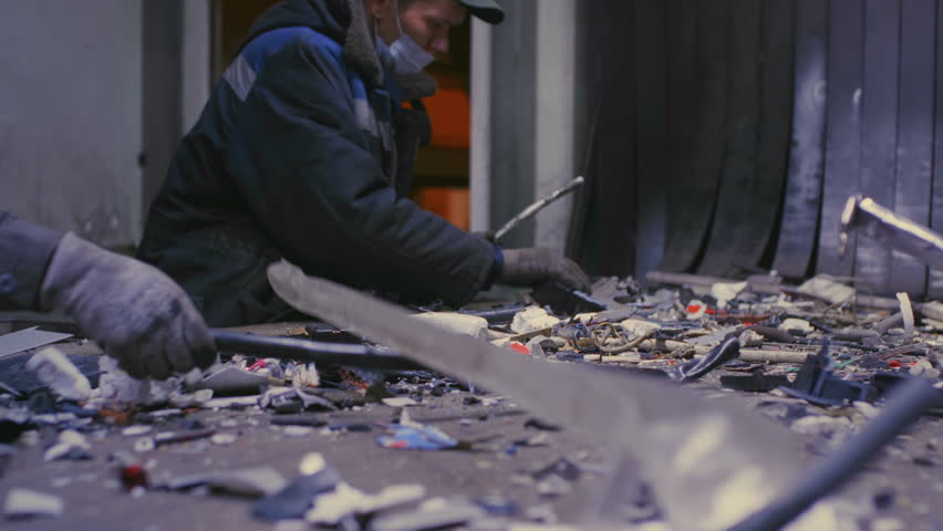 Workers stand at conveyor looking for non-recyclable waste among stream of garbage slow motion. Team tirelessly sorts through materials despite conveyor belt relentless pace at