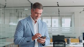 Busy middle aged business man ceo investor standing in office using mobile cell phone. Mature businessman professional entrepreneur looking at smartphone at work making baking payment. - Powered by Shutterstock - Get 15% off with code: PIKWIZARD15