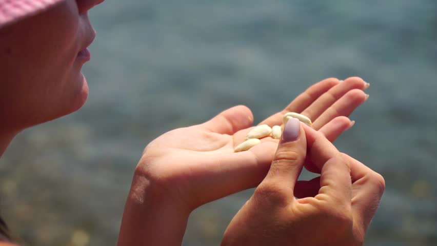 Woman eating milky almond nuts. Happy caucasian woman in pink hat eating fresh almond after morning fitness yoga near sea. Only hands are visibly. Healthy vegan food. Slow motion