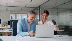 Two happy professional business partners executive leaders managers wearing suits working in office looking at computer technology discussing digital strategy together at corporate meeting. - Powered by Shutterstock - Get 15% off with code: PIKWIZARD15