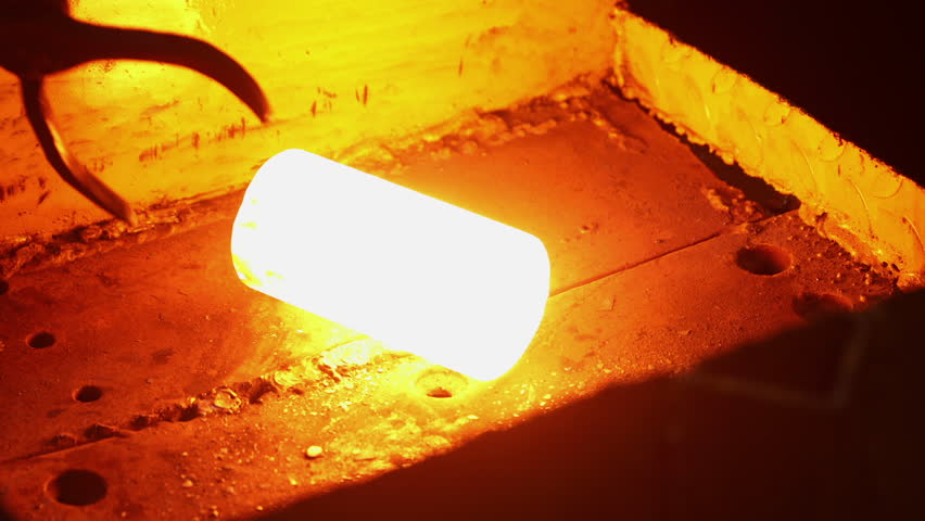 billet lifting tongs. large tongs are liftng picking up heated hot metal billet. forging processes in forging component manufacturing factory