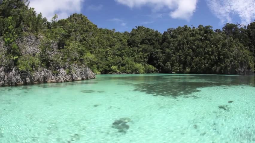Limestone islands, topped by tropical vegetation, drop to coral reefs in Raja