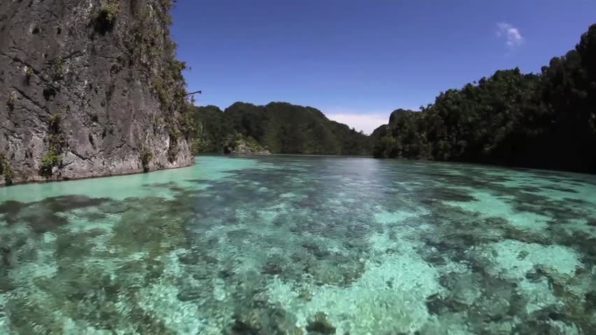 Limestone islands, topped by tropical vegetation, drop to coral reefs in Raja