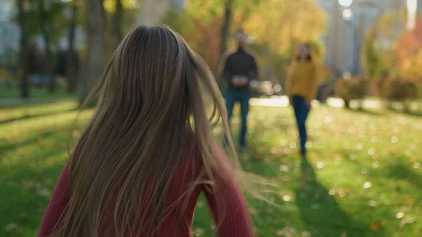 Happy Caucasian family in park parents with little child kid play game outdoors autumn daughter girl run dad running to daddy raise lift up in air spin funny playing having fun together love holiday