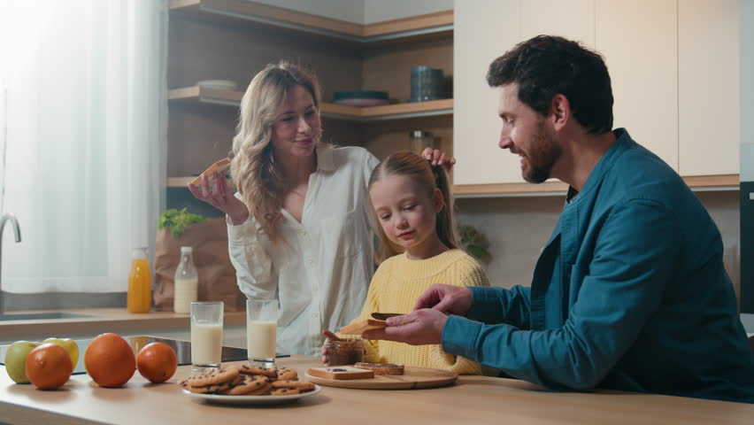 Happy Caucasian family medical insurance loan mortgage credit parents child kid daughter breakfast together at kitchen home food delivery healthy eating chocolate sandwich mother, father little girl Royalty-Free Stock Footage #3484124565