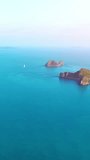 Aerial shot, flying and tilt towards a paradise island. Amazing small island High angle view. Aerial vertical, vertical video background.