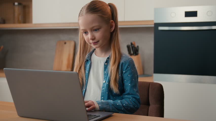 Caucasian little school girl child baby kid schoolgirl daughter at home kitchen using laptop browsing website children and modern technology generation studying learning distant online with computer Royalty-Free Stock Footage #3484157009