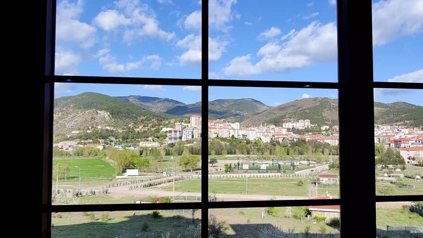 The video shows a general view of Ankara Kızılcahamam from a window with a panoramic view. Through the window, one can see a deep blue sky with scattered clouds.