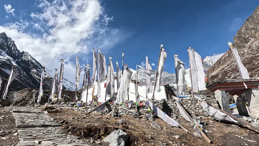 White prayer flags in the wind in front of icy valley of Kyanjin Gompa. Langtang valley trek, Himalayas, Nepal