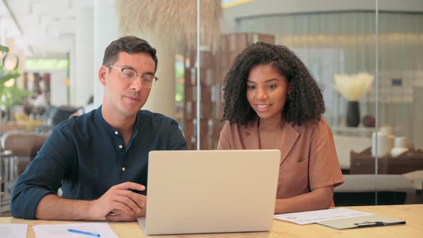 Creative professional business team of two diverse employees man and woman, manager and client using laptop computer technology discussing online project ai data working in office at work meeting.