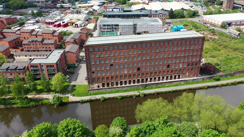 Aerial footage of regeneration construction work being done and an old mill building by the canal in the city of Leeds in the UK West Yorkshire