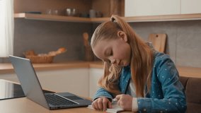 Moving camera Caucasian kid girl schoolgirl listen online lesson school class at home writing homework. Quarantine distant education. Child daughter studying remote with laptop e-learning at kitchen - Powered by Shutterstock - Get 15% off with code: PIKWIZARD15