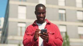Happy young African Black man hipster standing on city street outdoors holding smartphone using mobile apps looking at cell phone technology device chatting in social media, dating applications. - Powered by Shutterstock - Get 15% off with code: PIKWIZARD15