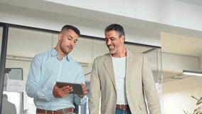 Busy professional executive business team of two men working together walking in office holding tab using digital tablet computer tech managing data talking going in corporate office hallway - Powered by Shutterstock - Get 15% off with code: PIKWIZARD15