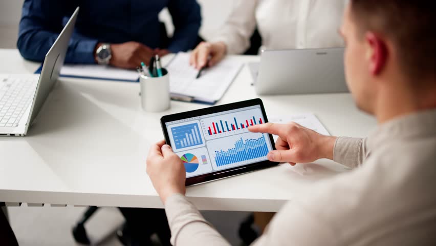 Predictive Business Analytics On Tablet Computer. Group Of Analysts