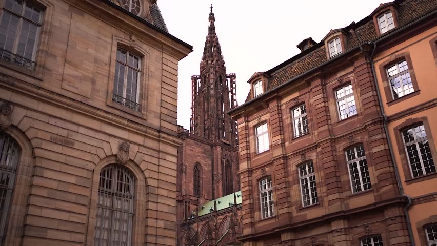 Strasbourg Notre-Dame Cathedral tower view through typical buildings on cloudy day, France Royalty-Free Stock Footage #3484347887