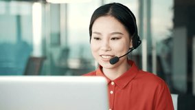 Asian woman in a headset customer service operator talking on a video call while sitting in business office. Call center agent advises the client by answering questions using laptop computer. Close up - Powered by Shutterstock - Get 15% off with code: PIKWIZARD15