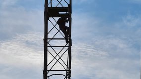 Silhouette of a male antenna tower maintenance technician doing dangerous work. The worker is descending the metal ladder tower. Dangerous work at height - Powered by Shutterstock - Get 15% off with code: PIKWIZARD15