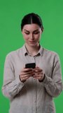 Surprised Woman Receiving Good News In Cellphone On Green Background