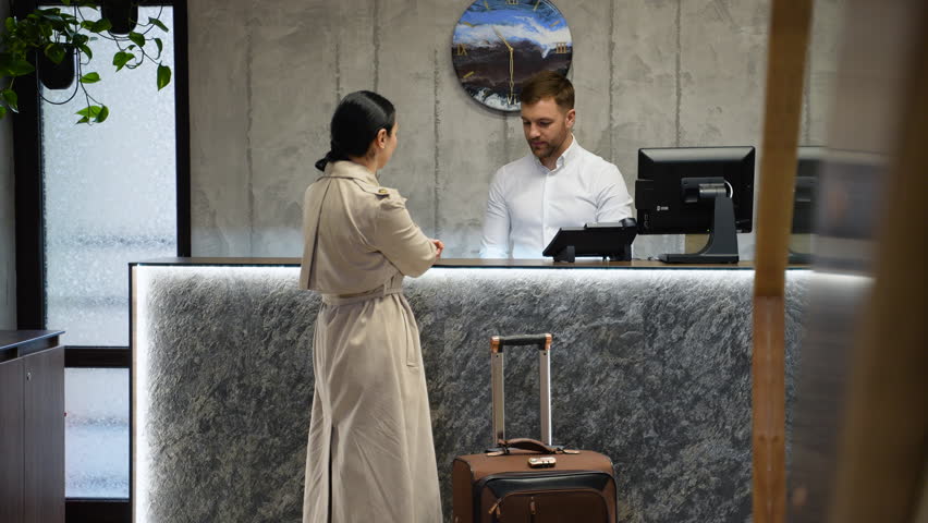 Businesswoman at the reception of a hotel checking in. Guest getting key card in hotel