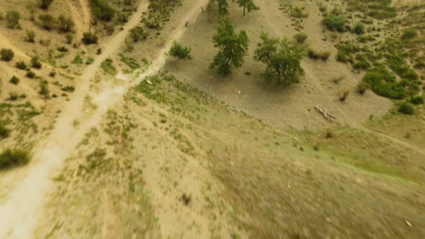 Moto racer rides along dirt road uphill fpv. Rider maneuvers vehicle on wild offroad land at motocross racing. Enjoying of speed and motion