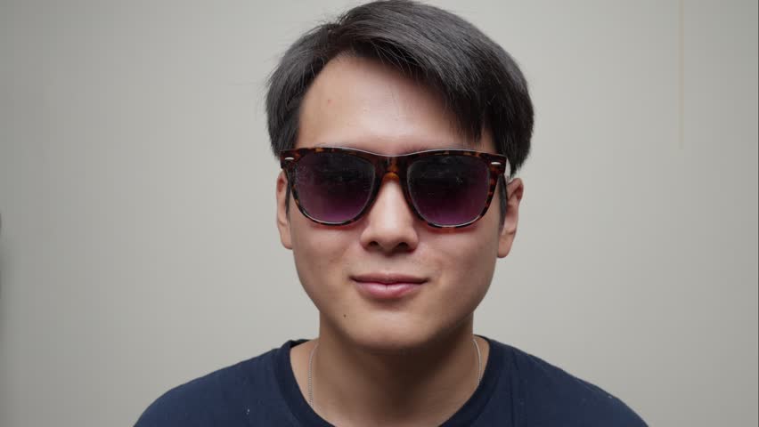 Portrait Of Asian Young Man Removing Fashion Elegant Sunglasses, Facing The Camera