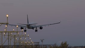Big commercial airplane with extended landing gear approaching runway during evening, with runway lights visible - Powered by Shutterstock - Get 15% off with code: PIKWIZARD15