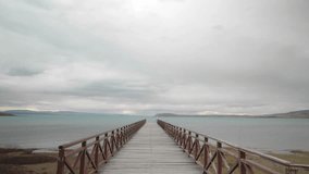 Long wooden pier ahead towards Argentino Lake on an overcast day