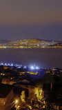 Timelapse, vertical video: view of city of Istanbul from the Princes Islands at night. Apartment, residential buildings with blinking illuminated windows. Fast moving ferries, motor boats: time lapse