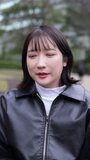 Vertical slow-motion video of a Japanese woman in her 20s sitting in a park around Gotanda Station, Shinagawa-ku, Tokyo in winter