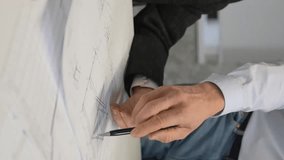 Close-up of the hands of colleagues with blueprints on the table in the office. Brainstorming of engineers and architects. Vertical video.  - Powered by Shutterstock - Get 15% off with code: PIKWIZARD15