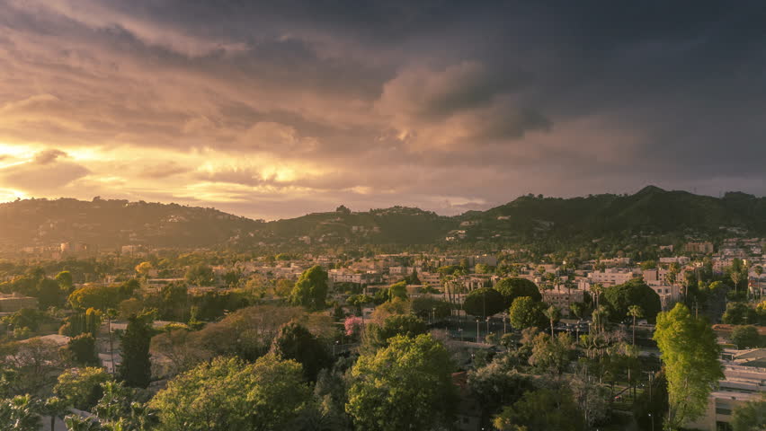 Hollywood, Los Angeles cityscape at sunset during golden hour, aerial hyperlapse view establishing shot.