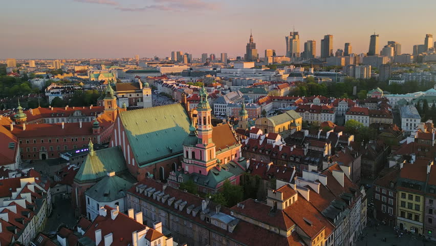 aerial view drone of warsaw old town city historic centre at sunset,flying to castle square with modern district with high-rise buildings in the background