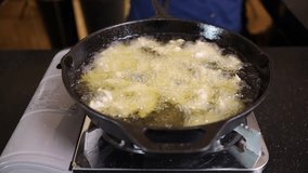the process of deep frying chicken. Professional cooking technique resulting in crispy and golden-brown fried chicken. Culinary perfection in action.
