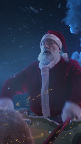 Senior man in Santa Claus costume grasping reins and urging reindeer forward then stopping sled against clouds and moon in night sky on Christmas eve. Vertical shot