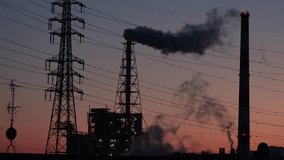 SHIZUOKA, JAPAN - MARCH 2024 : View of factory area in sunset. High chimney puffing clouds of black smoke heavenward. Earth environment, pollution and industry concept video. Time lapse shot.