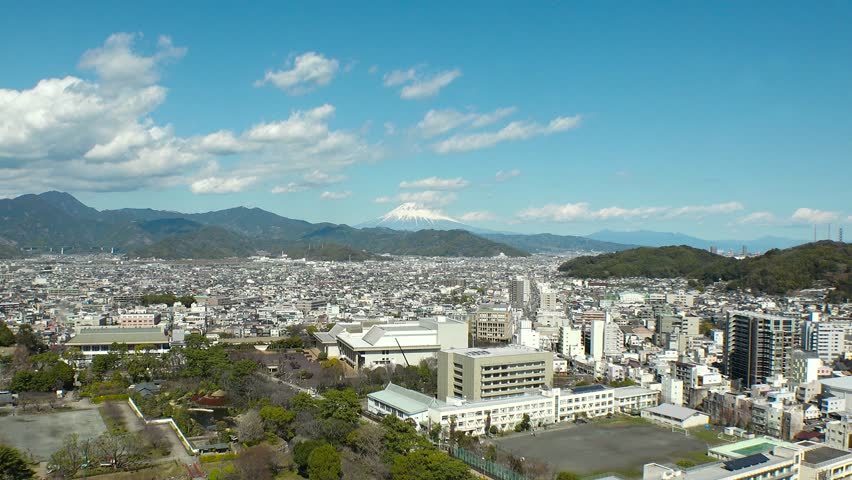 SHIZUOKA, JAPAN - MARCH 2024 : Aerial high angle view of cityscape of Shizuoka city and Mount Fuji. View of street around downtown area. Time lapse shot in daytime.
