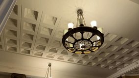 Riga, Latvia - April 4, 2024 - An ornate chandelier hanging from a decorative coffered ceiling in an elegant room. - Powered by Shutterstock - Get 15% off with code: PIKWIZARD15