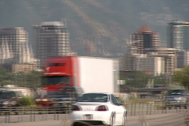 Freeway traffic and an urban cityscape in front of a towering mountain range.