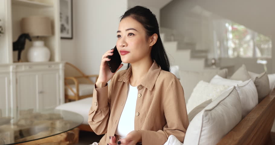 Pretty Asian woman lead pleasant conversation on smartphone at home, talk to friend about events, discuss daily routines or latest personal news, sharing rumors, chatting remotely using modern phone Royalty-Free Stock Footage #3484641857