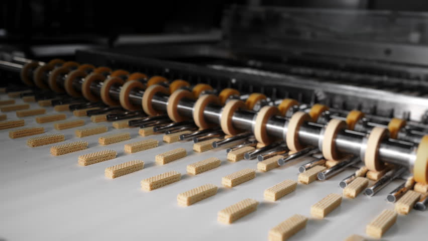 Wafer bars being cut on an automated production line, showing precise industrial food processing on conveyor in factory environment.