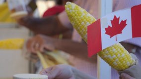 Canada Surrey Hot corn and Canada flag sprinkle salt on the corn Canada Day Families, people dressed in red, walk in the square on a holiday weekend - Powered by Shutterstock - Get 15% off with code: PIKWIZARD15