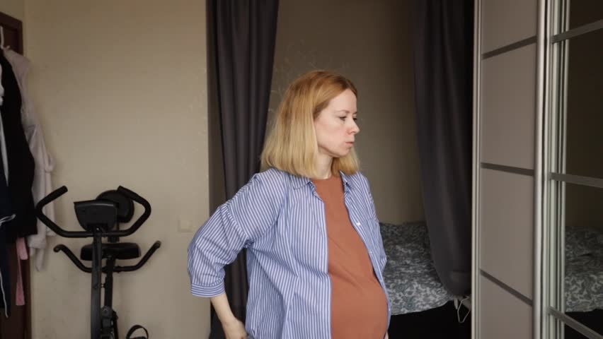 Pregnant woman suffering from back pain, expecting mother holding her lower back, discomfort during pregnancy Royalty-Free Stock Footage #3484809423