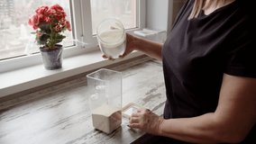 woman transfers flour from a glass jar into a plastic storage container - Powered by Shutterstock - Get 15% off with code: PIKWIZARD15