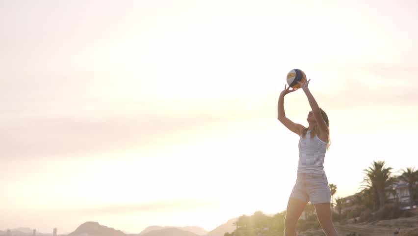 Close-up, female volleyball player making a pass from above at sunset on the beach.