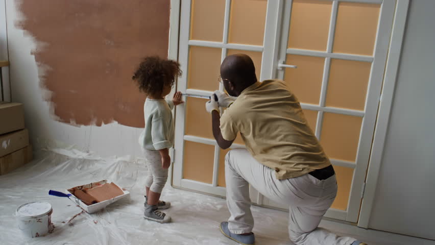 Back footage of little Biracial girl holing measuring tape from one edge helping dad measure door during room renovation Royalty-Free Stock Footage #3484892415